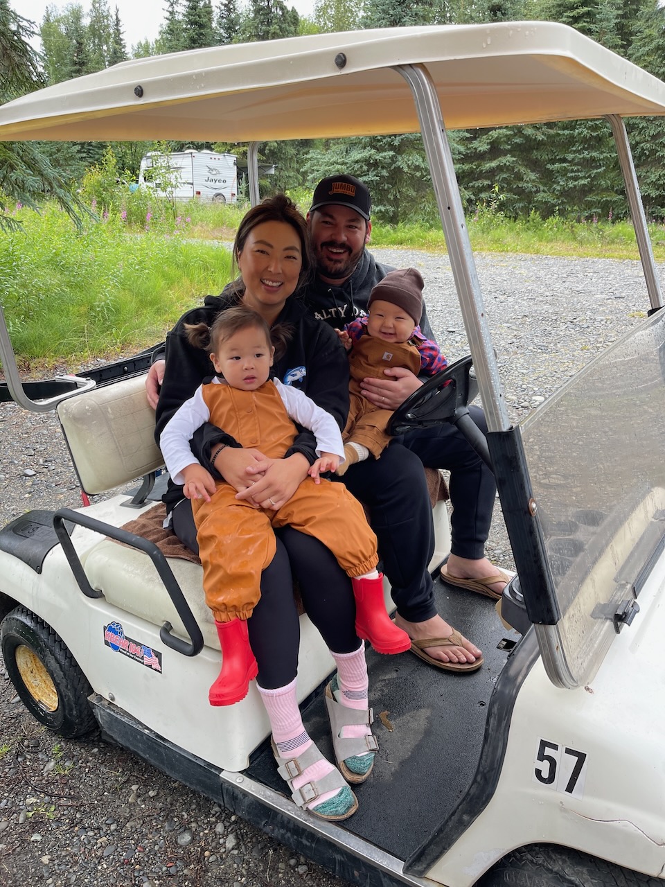 Janelle and her husband on golf cart 57 with both toddlers on their laps