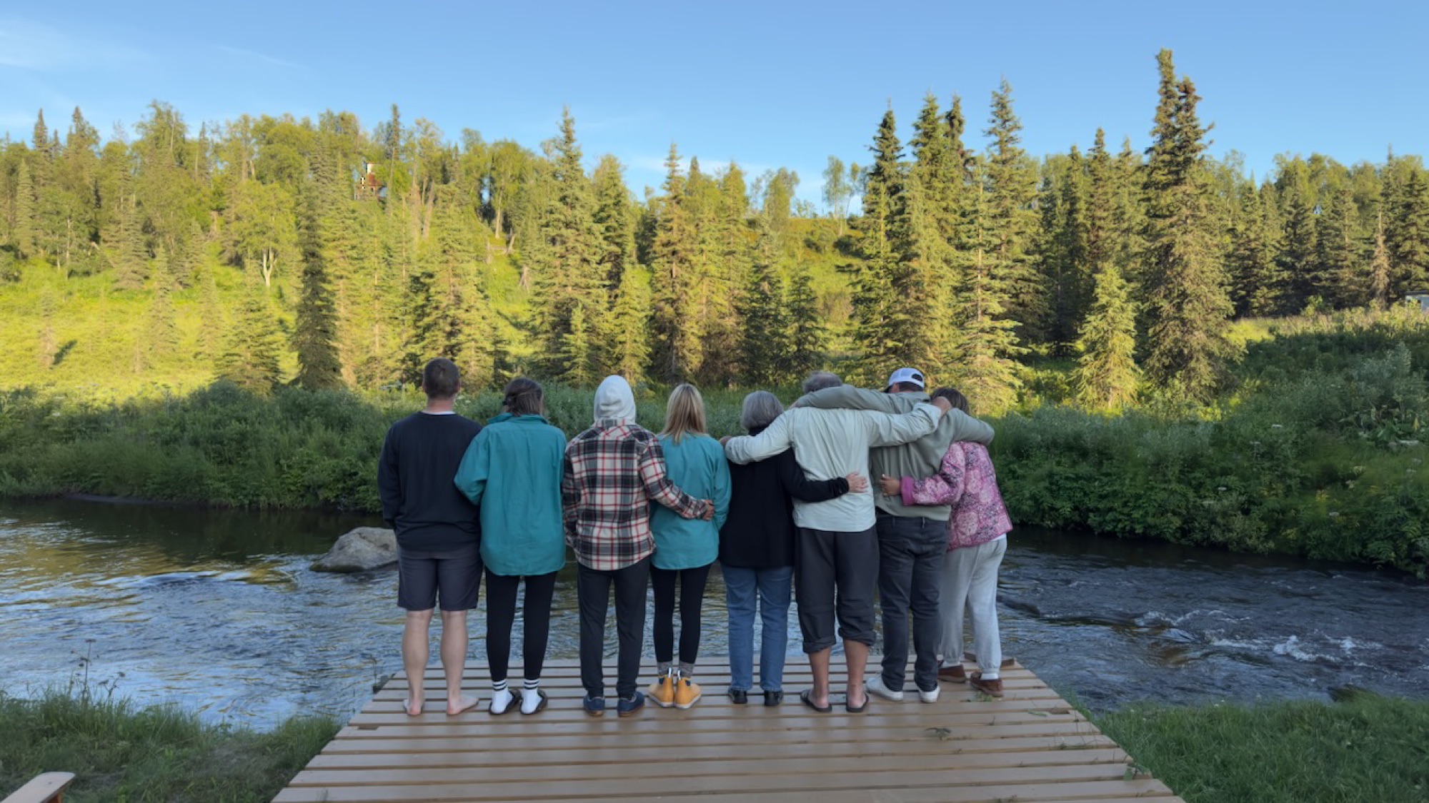 Eight Knepper family members on the dock at sunset, arms around each other, looking out at the river